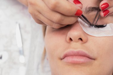 Kirpik uzatma ustası uzun kirpikleri güzellik salonunda güzel bir kız. Kirpik uzatma işlemi.