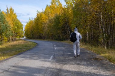 Sırt çantalı gezgin ya da gezgin sonbahar ormanlarında yola çıkar. Yürüyüş. Otostop çekiyordum.