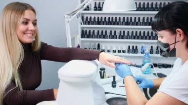 Nizhnevartovsk, Rusya - 12 Ağustos 2019: Usta manikür salonundaki tırnak jölesine vernik çizimi uyguluyor