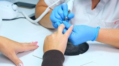 Manikür salonunda elektrikli çivi matkabı. Güzellik salonunda hırdavatçı manikürü. Kadın manikürcü müşterilerin tırnaklarından eski jeli alıyor. Vakum ızgarası. Güzellik salonunda çivi manikürü..