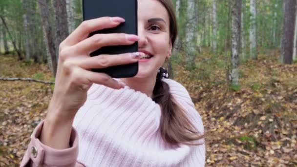 Fröhliche Frauen, die miteinander telefonieren. Mädchen macht Selfie im Herbstwald. — Stockvideo