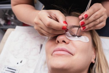 Kirpik uzatma ustası uzun kirpikleri güzellik salonunda güzel bir kız. Kirpik uzatma işlemi.