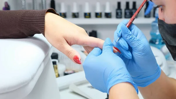 Manicure coloca gel polonês nas unhas de um cliente em um salão de beleza — Fotografia de Stock