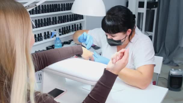 Manicurista presenta una uña con una lima de uñas a un cliente. Proceso de manicura, extensión de uñas . — Vídeos de Stock