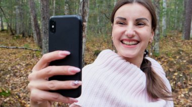 sonbahar ormanda gülen kadın skype telefonda konuşurken.