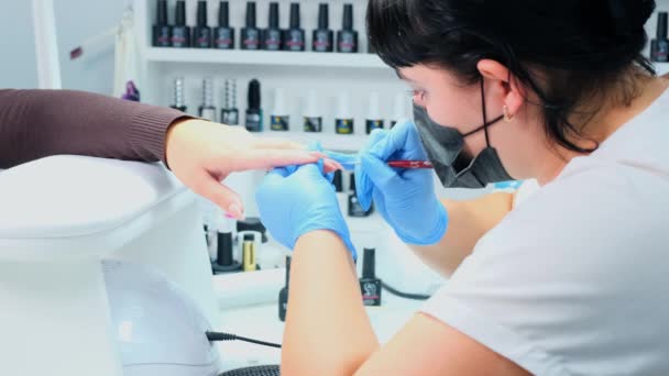 Manicure verft nagels aan een klant in een schoonheidssalon. Gel poetsmiddel. Lak maar. Manicure. Nagelverlenging — Stockvideo