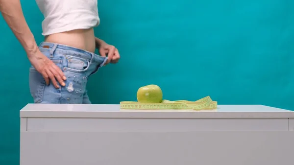Θηλυκό αδυνατισμένο στομάχι και πράσινο μήλο σε πρώτο πλάνο, επιλεκτική εστίαση. Η έννοια της απώλειας βάρους και της σωστής διατροφής — Φωτογραφία Αρχείου