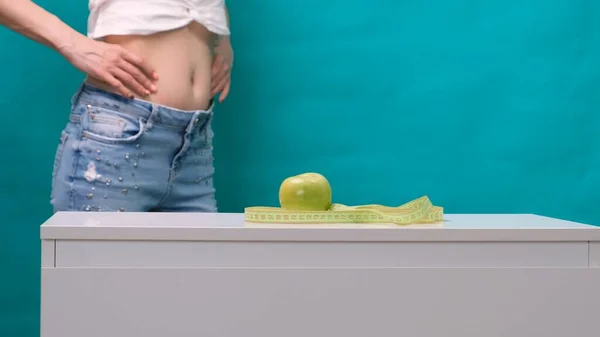 Női karcsúsított gyomor és zöld alma az előtérben, szelektív fókusz. A fogyás és a megfelelő táplálkozás fogalma — Stock Fotó