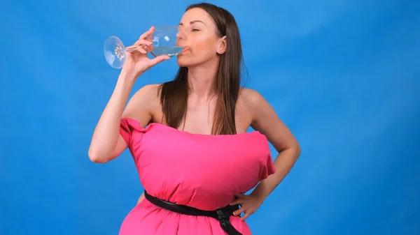 Najpiękniejsza dziewczyna w różowej sukience z poduszek ze szklanką wina na niebieskim tle. Szalona kwarantanna. Moda 2020. Załóż poduszkę. Wyzwanie 2020 ze względu na izolację domów. — Zdjęcie stockowe