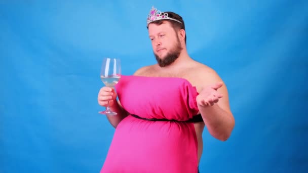 Funny bearded guy in a pink dress made of pillows in a crown with a glass of wine on a blue background. Crazy quarantine. Funny house cleaning. Fashion 2020. Put on a pillow. Challenge 2020 due to — Stock Video