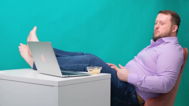 Close-up Zakenman is lui op het werk met poten op tafel die chips eten. Het begrip verveling en vermoeidheid op het werk — Stockvideo