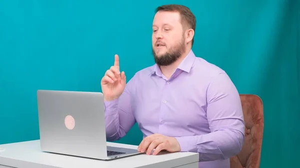 Giovane uomo d'affari felice tiene una riunione di conferenza in un computer portatile su uno schermo verde. Ritratto di un uomo parlante che guarda nel suo portatile. Uomo che lavora alla sua scrivania in ufficio — Foto Stock