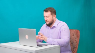 Genç mutlu iş adamı yeşil ekranda bir dizüstü bilgisayarda toplantı yapıyor. Dizüstü bilgisayarına bakan konuşan bir erkeğin portresi. Ofisteki masasında çalışan bir adam.