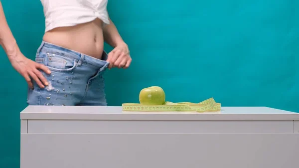 Weiblicher schlanker Bauch und grüner Apfel im Vordergrund, selektiver Fokus. Das Konzept der Gewichtsabnahme und der richtigen Ernährung — Stockfoto