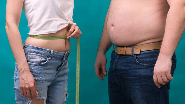 Pár Tlustých mužů a hubených žen, stojící spolu, zabaleni v magnetofonu. Dieta, ztráta hmotnosti rodiny a koncepce zdravotní péče. — Stock fotografie