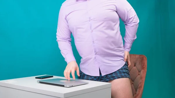 Work from home concept. Businessman having a conference call on a laptop with no pants. young man in a blue shirt and underwear works at home, working on a laptop — Stock Photo, Image