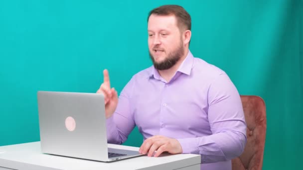 Werk vanuit huis concept. Zakenman die een conference call houdt op een laptop zonder broek. jonge man in een blauw shirt en ondergoed werkt thuis, werken aan een laptop — Stockvideo