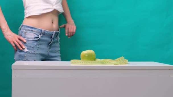 Женский стройный желудок и зеленое яблоко на переднем плане, избирательный фокус. Концепция потери веса и правильного питания — стоковое видео
