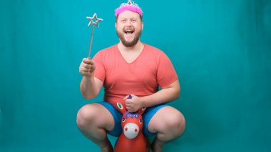 Elinde sihirli bir değnekle tek boynuzlu ata binen pembe tişörtlü, sakallı, garip bir adam. Bir dileği gerçekleştirmek için komik bir sihirbaz şakası..