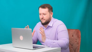 Genç mutlu iş adamı yeşil ekranda bir dizüstü bilgisayarda toplantı yapıyor. Dizüstü bilgisayarına bakan konuşan bir erkeğin portresi. Ofisteki masasında çalışan bir adam.