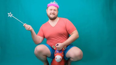 Elinde sihirli bir değnekle tek boynuzlu ata binen pembe tişörtlü, sakallı, garip bir adam. Bir dileği gerçekleştirmek için komik bir sihirbaz şakası..