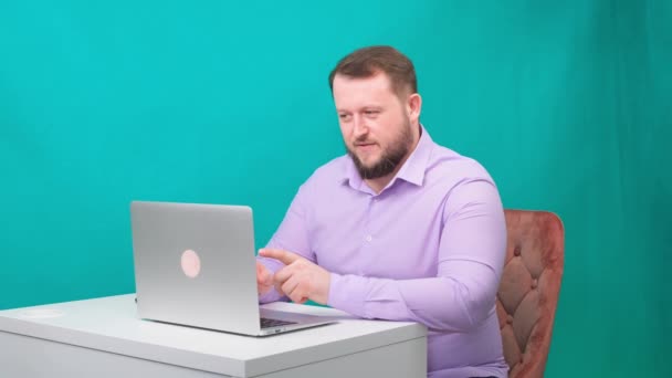 Práce z domova. Podnikatel má konferenční hovor na notebooku bez kalhot. mladý muž v modré košili a spodním prádle pracuje doma, pracuje na notebooku — Stock video