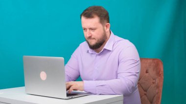 Genç mutlu iş adamı yeşil ekranda dizüstü bilgisayarda yazıyor. Dizüstü bilgisayarına bakan konuşan bir erkeğin portresi. Ofisteki masasında çalışan bir adam..