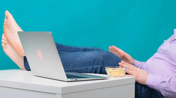 Крупним планом чоловічі ноги на робочому столі біля ноутбука. Поняття нудьги і втоми на роботі . — стокове фото
