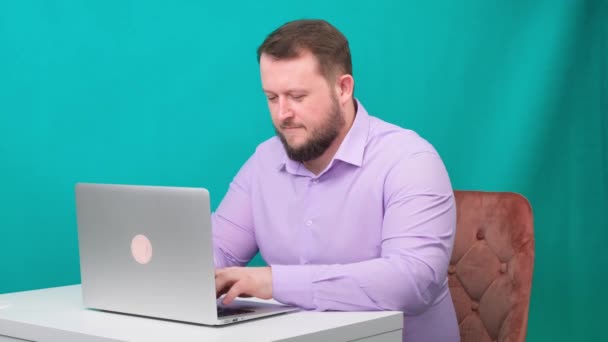 Jonge gelukkige zakenman typt op laptop op groen scherm. Portret van een pratende man die in zijn laptop kijkt. Man werkt aan zijn bureau in het kantoor. — Stockvideo