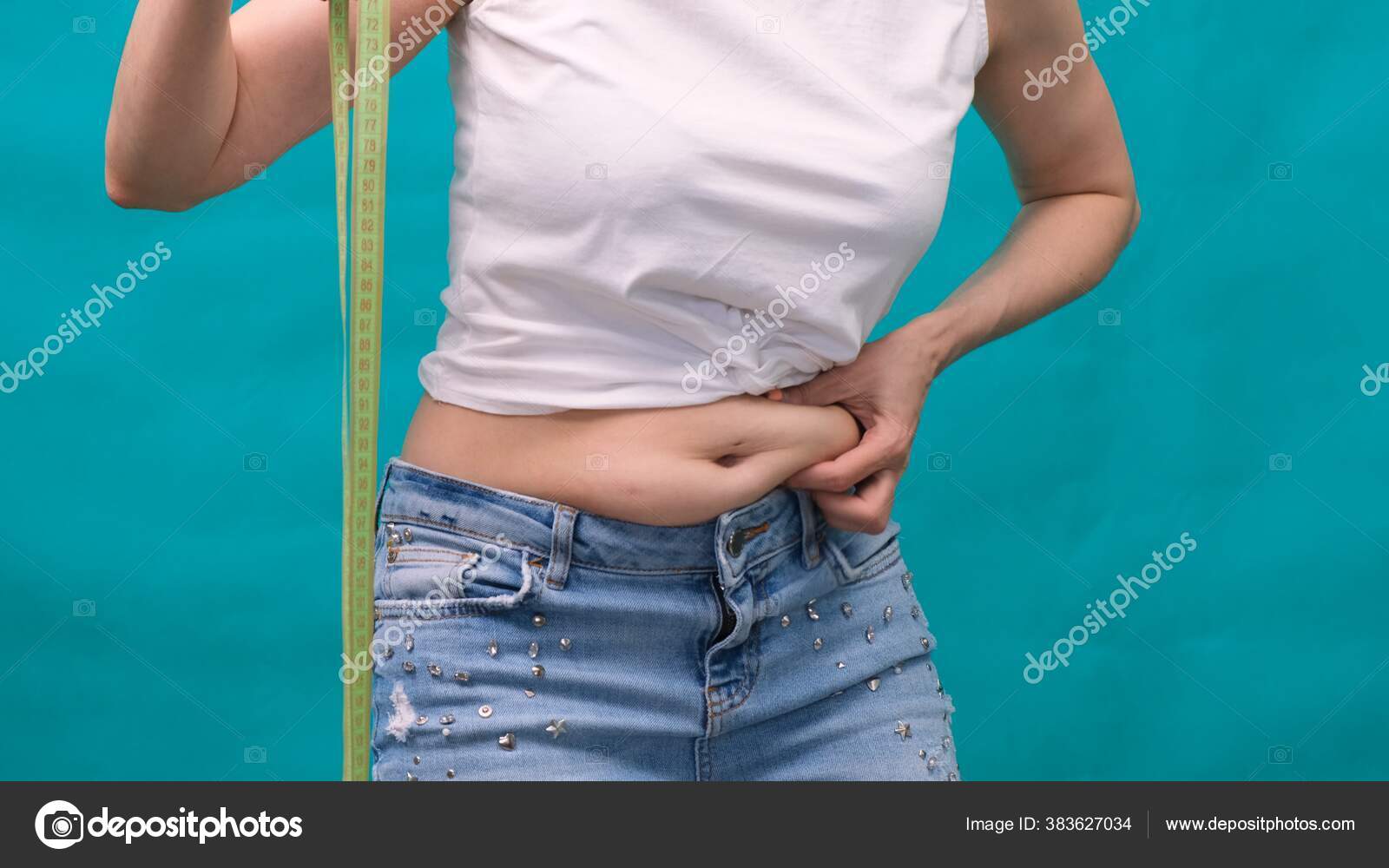 Vrouw houdt een huidplooi op een dikke buik, vet vrouwelijk