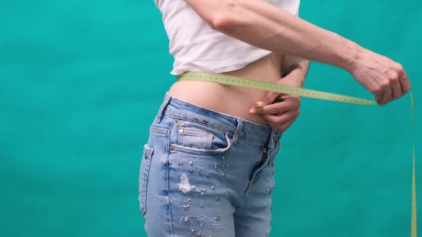 Close-up de uma mulher mede sua cintura, conceito de dieta, perda de peso e nutrição adequada . — Vídeo de Stock