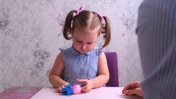 Glücklich lächelndes kleines Mädchen macht mit ihren Händen eine Krähe mit ihrer Mutter. Alltagsmamas Mädchen beim Malen und Basteln im Klassenzimmer im Kindergarten. — Stockvideo