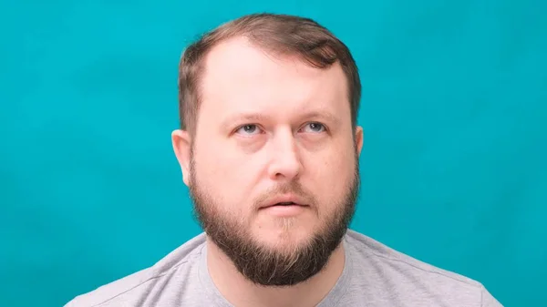 Bearded man looks surprised in horror on a green background — Stock Photo, Image