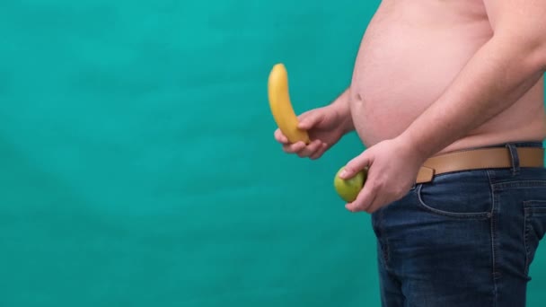 Hombre gordo con un vientre grande sostiene una manzana verde en su mano. El concepto de alimentación saludable y pérdida de peso, dieta . — Vídeo de stock