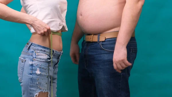 Pareja hombre gordo y mujer delgada de pie juntos, envueltos en cinta métrica. Dieta, pérdida de peso familiar y concepto de atención médica . — Foto de Stock