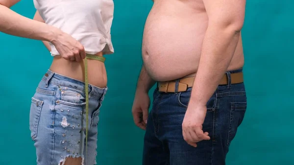 Dicker Mann und dünne Frau stehen zusammen, in Klebeband gewickelt. Ernährung, Gewichtsverlust in der Familie und Gesundheitskonzept. — Stockfoto