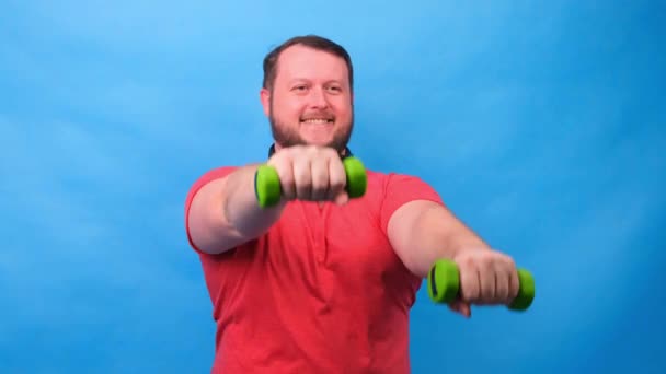 Fantaisie mâle dans un t-shirt rose avec haltères drôle faire des exercices sur un fond bleu — Video