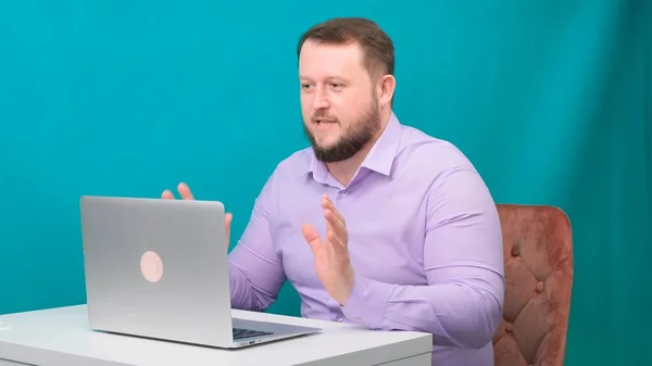 Jeune homme d'affaires heureux tient une réunion de conférence à un ordinateur portable sur un écran vert. Portrait d'un homme parlant regardant dans son ordinateur portable. Homme travaillant à son bureau dans le bureau — Photo