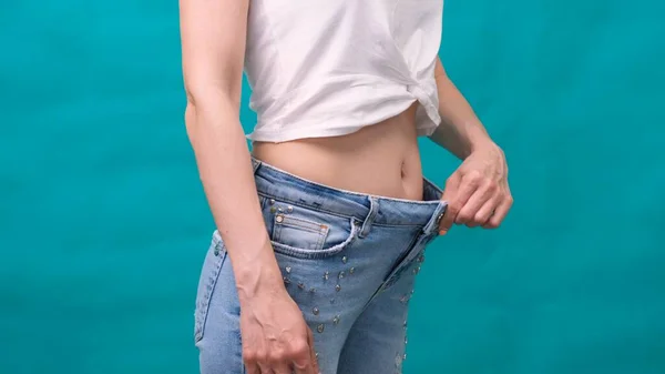 Приваблива молода жінка носить джинси і показує тонке тіло після спортивних тренувань і здорового харчування. Концепція втрати ваги . — стокове фото