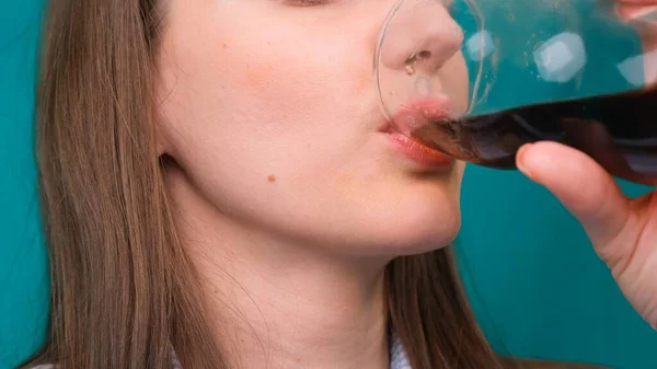 Primer plano de una mujer bebiendo una bebida oscura de un vaso . — Foto de Stock