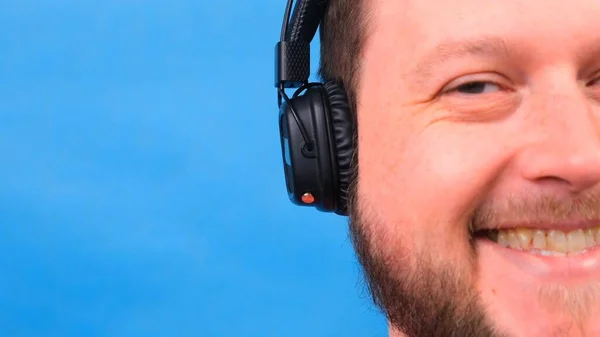 Homem gordo carismático alegre em fones de ouvido isolados e camiseta rosa em um fundo azul. ouvir música, cantar e dançar — Fotografia de Stock