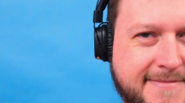 Kulaklıklı neşeli, karizmatik şişman adam izole edilmiş ve mavi arka planda pembe tişört. müzik dinlemek, şarkı söylemek ve dans etmek.