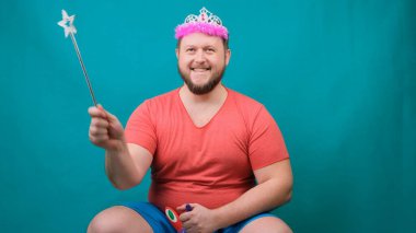 Kafasında diyademiyle pembe tişörtlü sevimli sakallı ucube adam elinde sihirli bir değnekle tek boynuzlu ata binmeyi hayal ediyor. Bir dileği gerçekleştirmek için komik bir sihirbaz şakası.