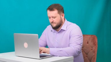 Genç mutlu iş adamı yeşil ekranda dizüstü bilgisayarda yazıyor. Dizüstü bilgisayarına bakan konuşan bir erkeğin portresi. Ofisteki masasında çalışan bir adam..