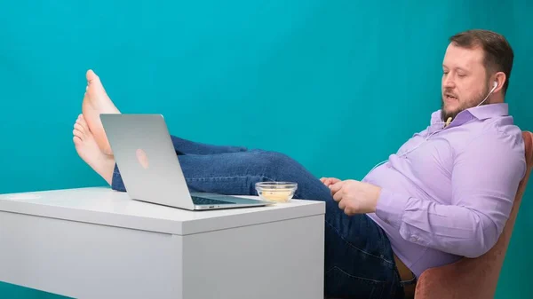 Großaufnahme Geschäftsmann, der am Arbeitsplatz faul ist und mit den Beinen auf dem Tisch Chips isst. Das Konzept der Langeweile und Ermüdung bei der Arbeit — Stockfoto