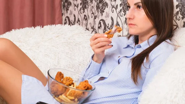 Joven mujer feliz comiendo pollo frito, primer plano. La mujer come alitas de pollo, ingesta de calorías y riesgos para la salud, colesterol — Foto de Stock