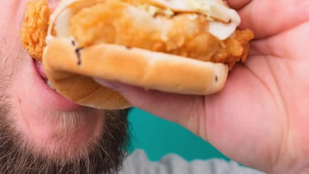 Gros plan d'un homme mordant un hamburger sur une Chroma Key. Le concept d'une alimentation malsaine et malsaine, un taux élevé de cholestérol. — Video