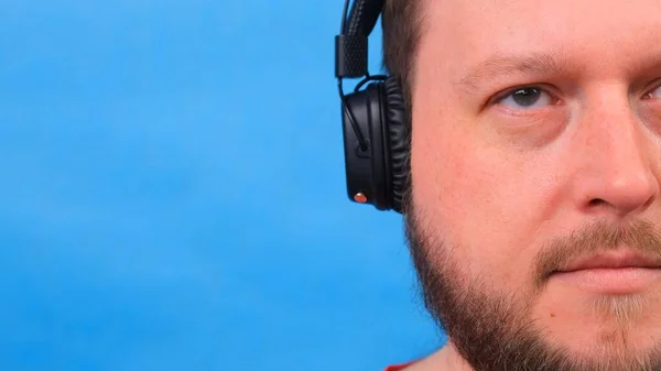 Hombre gordo carismático alegre en auriculares aislados y camiseta rosa sobre un fondo azul. escuchar música, cantar y bailar —  Fotos de Stock