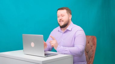 Genç mutlu iş adamı yeşil ekranda bir dizüstü bilgisayarda toplantı yapıyor. Dizüstü bilgisayarına bakan konuşan bir erkeğin portresi. Ofisteki masasında çalışan bir adam.