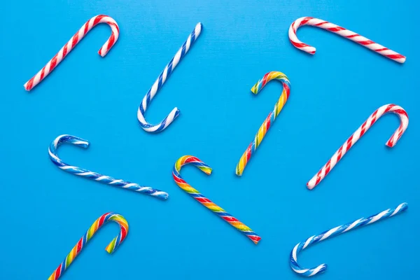 Lot of multi-colored candy canes on a blue background, copy space — Stock Photo, Image